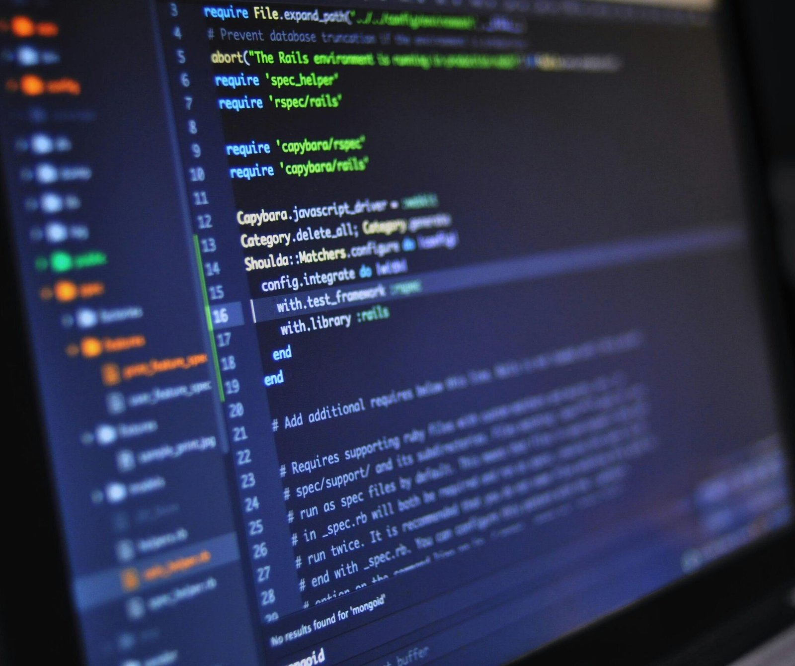 Close-up of a computer screen displaying programming code in a dark environment.